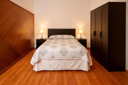 a bedroom with a bed and two lamps on two tables at La estación in Villafranca del Bierzo