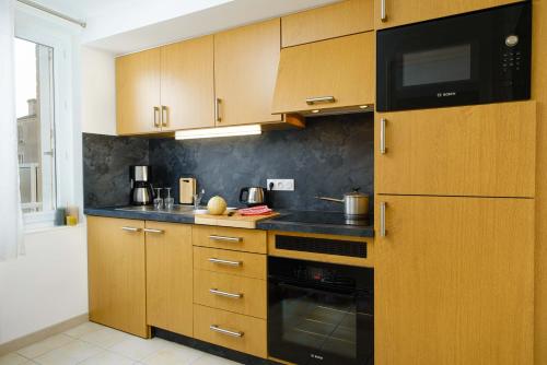 une cuisine avec des armoires en bois et un comptoir noir dans l'établissement Appartement Face à la Mer 1 chambre 2 personnes Saint Aubin sur Mer, à Saint-Aubin-sur-Mer