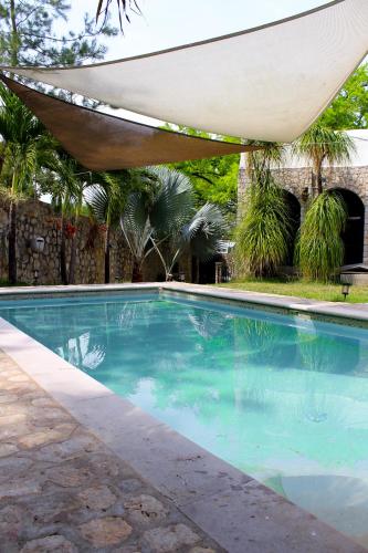 a swimming pool with a hammock over it at Hotel Boutique Canto De Piedra in Tamasopo