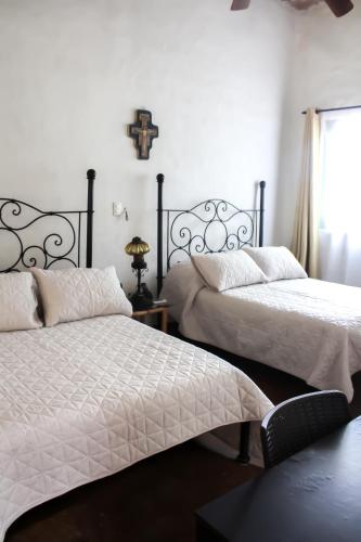 a bedroom with two beds and a cross on the wall at Hotel Boutique Canto De Piedra in Tamasopo