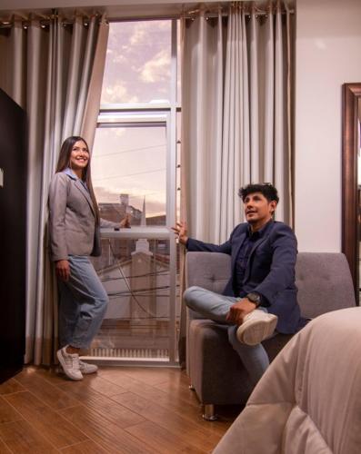 a woman standing next to a man sitting in a chair at Hotel Melthon Urbans in Ayacucho