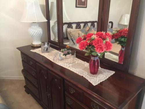 a wooden dresser with a vase of red flowers on it at 1506 Z2b VILLAGE OF SANTO DOMINGO by REMAX Premier in The Villages