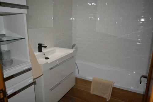 une salle de bain blanche avec un lavabo et une baignoire dans l'établissement Appartement tout à pied à Biarritz centre, à Biarritz