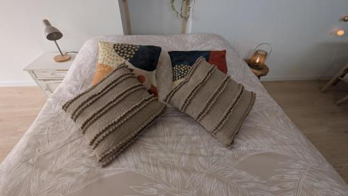 a bed with three pillows on top of it at Appartement cosy avec jardin in Meauzac