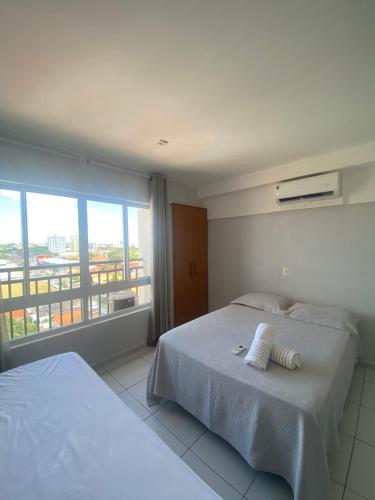 a bedroom with two beds and a large window at Apartamento Estúdio in Teresina