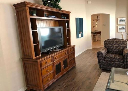 a living room with a television in a wooden entertainment center at 2474 Z3a VILLAGE OF ST JAMES by REMAX Premier in The Villages