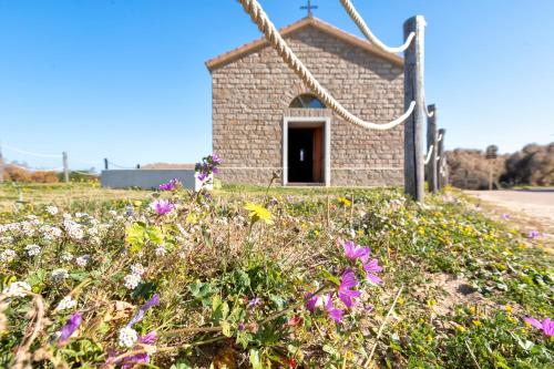 a small brick chapel with flowers in the foreground at Casa con terrazza nella Pineta in La Ciaccia