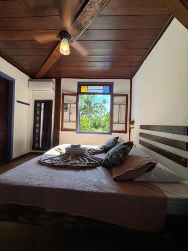 a large bed in a room with a window at Vila Pequeá Pousada Ilhabela in Ilhabela