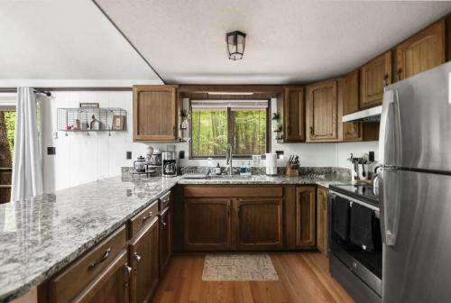 a kitchen with wooden cabinets and a stainless steel refrigerator at Cozy A-Frame w Fireplace Fire Pit Grill & WiFi in Hedgesville