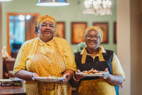 two women holding plates of food in a room at Acorn Guest House in George