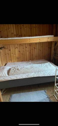 a large bed in a wooden room with a ladder at Rorbu Vestersia i Skjelfjord in Ramberg