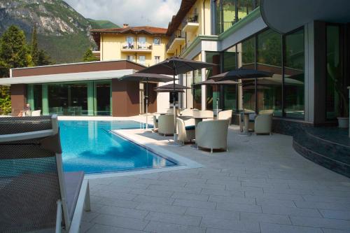 a pool with chairs and umbrellas next to a building at Villa Nicolli Romantic Spa Resort - Adults Only in Riva del Garda