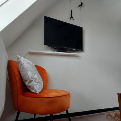 an orange chair with a television on a wall at The Rooftop Retreat - by The M House in Arnhem