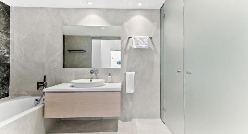 un bagno bianco con lavandino e specchio di Incredible Six Bedroom Frontline Villa 287 Aperion, Panoramic Sea Views, Aphrodite Hills a Kouklia