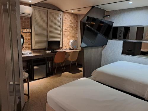 a room with two beds and a desk with a computer at hotel louize in Seoul