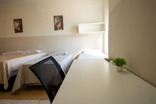 a room with two beds and a table with a plant at Hotel Centro in Corumbá