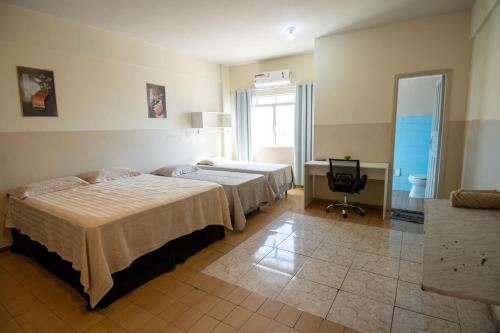 a hotel room with two beds and a television at Hotel Centro in Corumbá