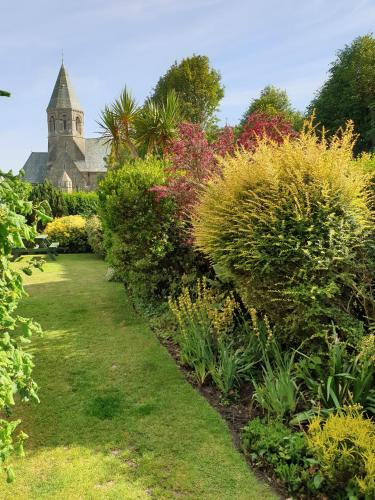 a garden with colorful bushes and a church in the background at The Wycliffe in Folkestone