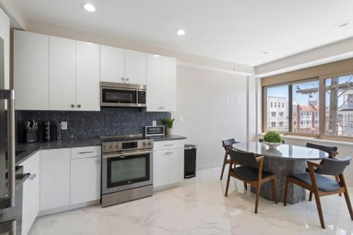 a kitchen with white cabinets and a table with chairs at Ammos Luxury Living- Zakinthos Suite in Ventnor City