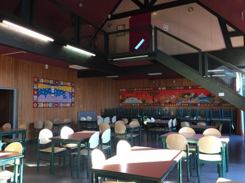 a dining room with tables and chairs and a staircase at Auberge de Jeunesse HI Saint-Brieuc in Saint-Brieuc