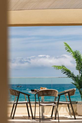 a table and chairs on a balcony with the ocean at Batis Beach Hotel in Rethymno Town