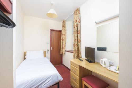 a bedroom with a bed and a desk with a television at The Sandringham Hotel in Weston-super-Mare