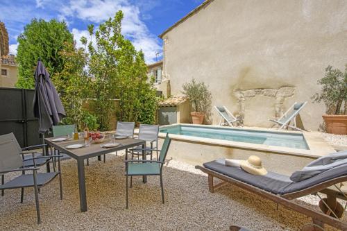 a patio with a table and chairs next to a pool at La Petite Maussanaise in Maussane-les-Alpilles