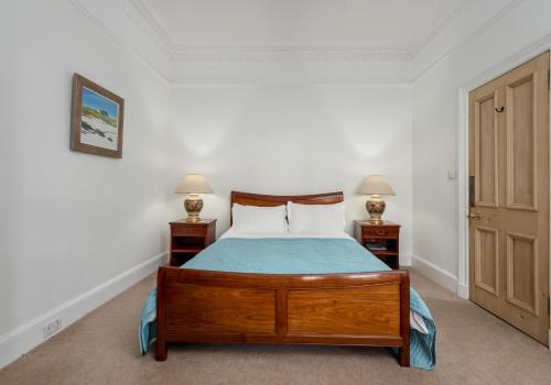 a bedroom with a wooden bed with two night stands at The Lauderdale Street Residence in Edinburgh
