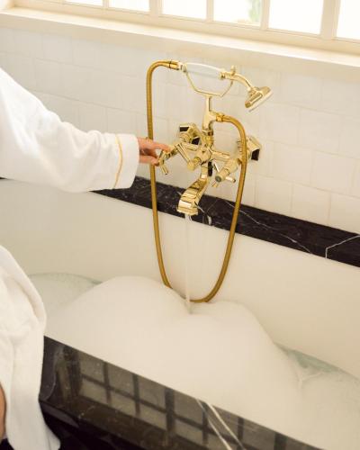 a person holding a shower in a bath tub at Relais Christine in Paris