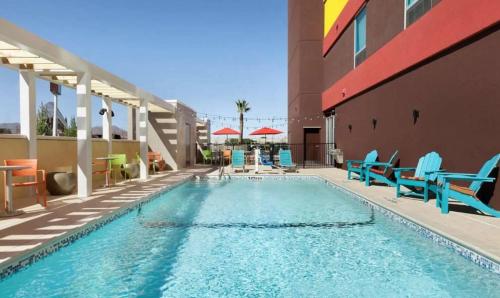 a swimming pool with blue chairs and a building at Home2 Suites By Hilton El Paso East Loop 375 in El Paso