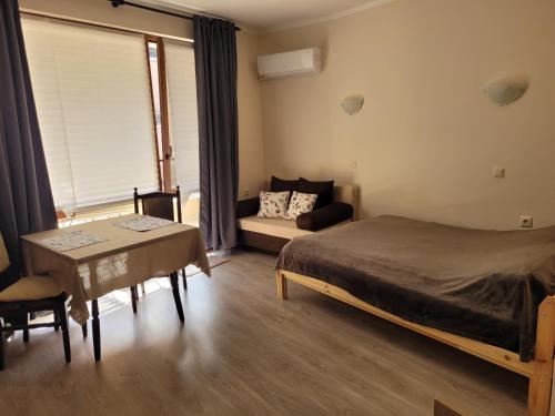 a bedroom with a bed and a couch and a table at На море в Сарафово in Burgas City