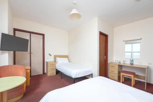 a hotel room with two beds and a television at The Sandringham Hotel in Weston-super-Mare