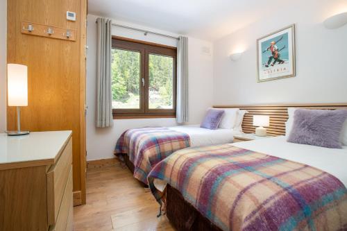 une chambre d'hôtel avec deux lits et une fenêtre dans l'établissement Peaceful Morzine Escape with Garden & Hot Tub, à Morzine