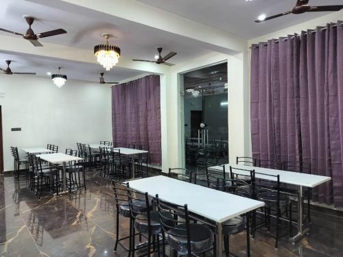 a row of tables and chairs in a room with purple curtains at Hotel Grand View in Barkot
