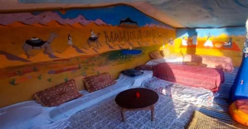 a bedroom with a bed and a painting on the wall at Desert Atmosphere M'Hamid in Mhamid