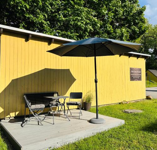 a table and two chairs and an umbrella on a deck at Alter Gutshof Kromlau Direkt am Schloss und Rhododendronpark, Terasse und Parkplatz in Kromlau