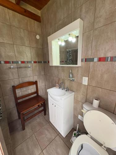 a bathroom with a toilet and a sink and a chair at Refugio de Rufina y Guadalupe in Chascomús