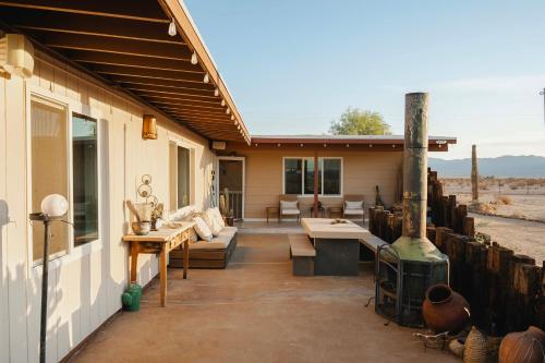 an outdoor patio with couches and a fireplace at Twentynine Palms Desert Oasis with Pool and Hot Tub! in Twentynine Palms