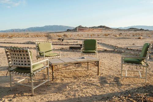 three chairs and a table in the desert at Twentynine Palms Desert Oasis with Pool and Hot Tub! in Twentynine Palms