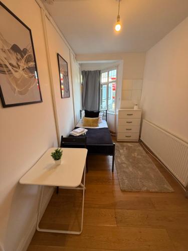 a small room with a bed and a table at Charming Stay House in Ealing