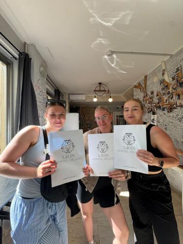 three people holding up paper signs in a room at Lion University & Youth Hostel Milano in Milan