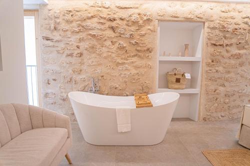 a bathroom with a tub and a couch and a chair at Vila Nova Suites & SPA in Capdepera