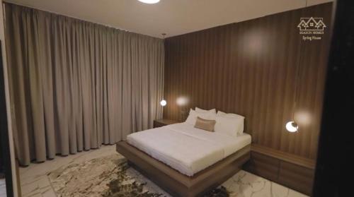 un dormitorio con una cama con sábanas y almohadas blancas en Kampala Apartments, en Kampala