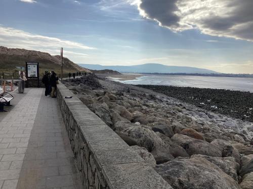 a group of people walking along a wall next to the beach at Gala House Strandhill in Strandhill
