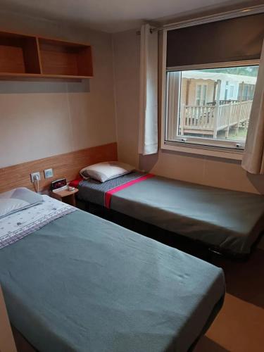 deux lits dans une petite pièce avec une fenêtre dans l'établissement Bungalow familial à Canet-en-Roussillon avec piscine, à Canet