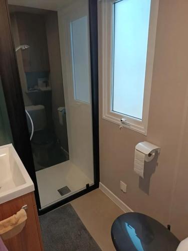 une salle de bain avec toilettes, lavabo et fenêtre dans l'établissement Bungalow familial à Canet-en-Roussillon avec piscine, à Canet