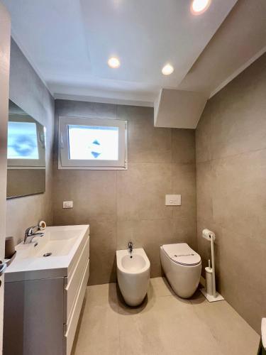 a bathroom with a sink and a toilet and a window at Salentoguests villetta sulla spiaggia in Porto Cesareo