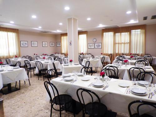 a room filled with tables and chairs with white table cloth at Hotel Adriana in Bellaria-Igea Marina