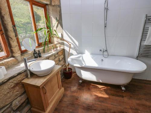 a bathroom with a bath tub and a sink at Pule Hill Farm in Huddersfield