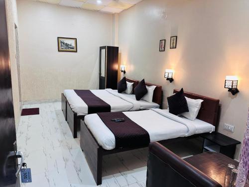 a hotel room with two beds and a couch at The Garden inn Varanasi in Varanasi